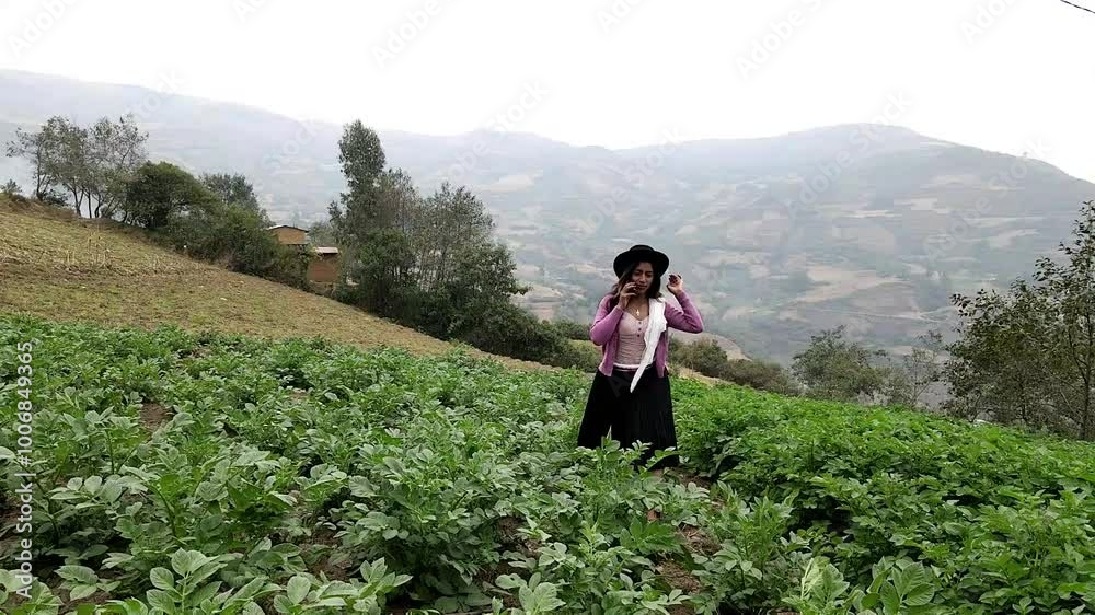 Video de una feliz y bonita campesina con un sombrero hablando por un teléfono celular en los Andes peruanos. Mujer usando teléfono móvil