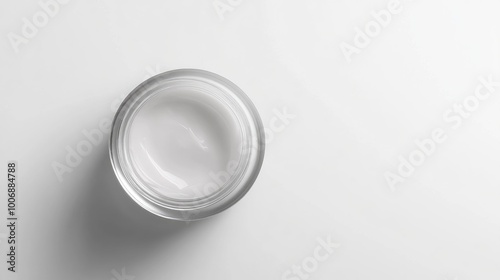 Close-up of moisturizer in a clear jar, top view, glossy finish. Smooth surface with no branding. Simple, minimalist white background.