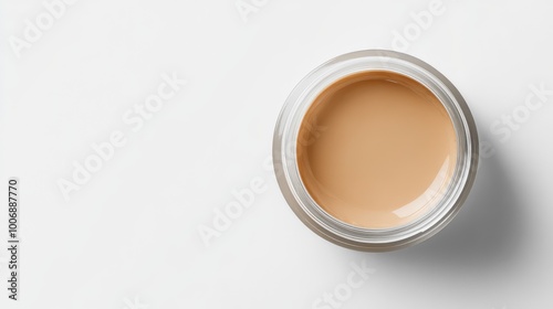 Smooth foundation cream in a clear jar, top view close-up. Glossy surface, no branding. Minimalist aesthetic with a plain white background.