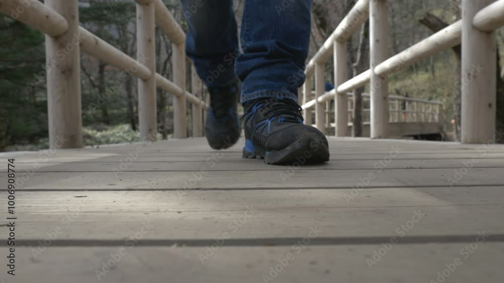 Close-up low-angle view of one man walking on bridge, focusing on their shoes and planks. movement with individual stepping forward, framed by wooden rails of bridge
Close-up low-angle view of one man walking on bridge, focusing on their shoes and planks. movement with individual stepping forward, framed by wooden rails of bridge