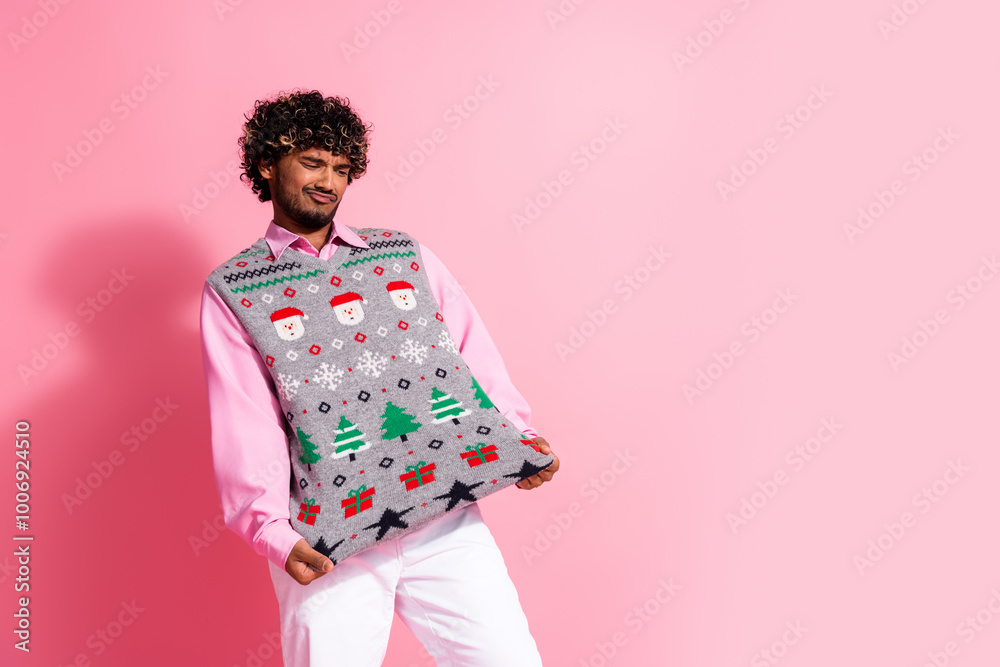 Portrait of nice young man show ugly new year xmas vest print empty space isolated on pink color background Portrait of nice young man show ugly new year xmas vest print empty space isolated on pink color background