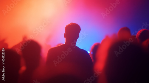 Excited concert crowd illuminated by vibrant stage lights, creating lively atmosphere. silhouette of person stands out against colorful backdrop, capturing energy of moment