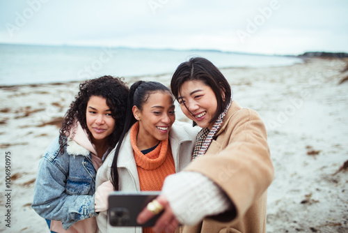 Three female friends taking selfie on the beach during winter photo