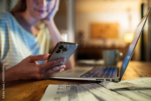 Woman late night working on laptop and smartphone at home