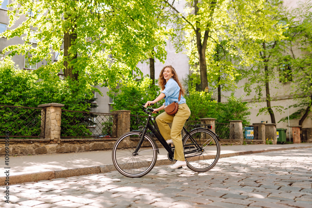 Naklejka premium Happy woman riding bicycle at the city street outdoor. Freedom on two wheels. Active lifestyle.