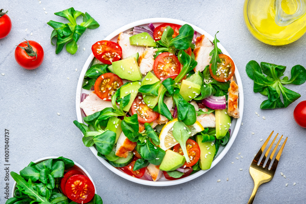 Fresh salad with avocado, chicken, tomatoes and lettuce, gray background, top view Fresh salad with avocado, chicken, tomatoes and lettuce, gray background, top view