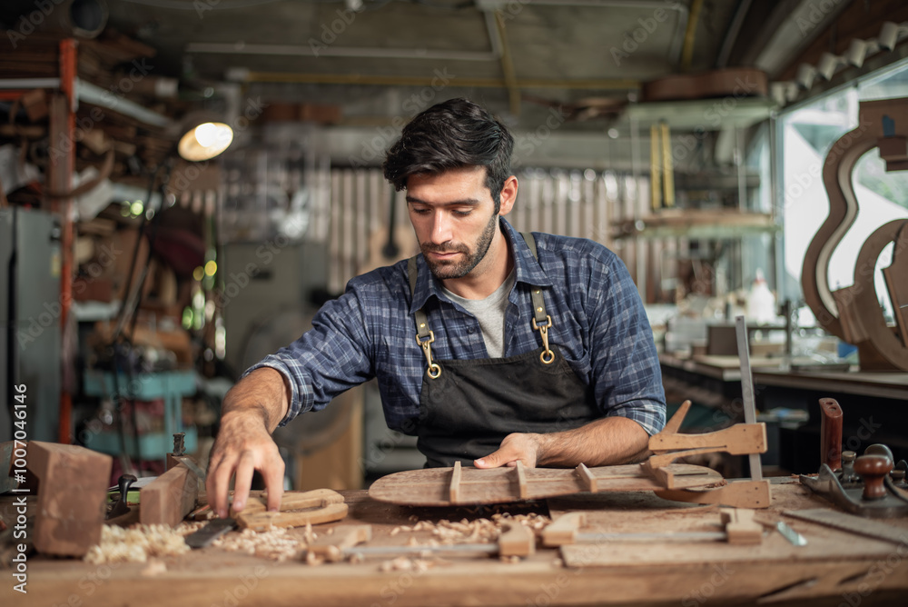 Luthier creating a guitar, clamps on the body of a guitar under construction improving glue adhesion Luthier creating a guitar, clamps on the body of a guitar under construction improving glue adhesion