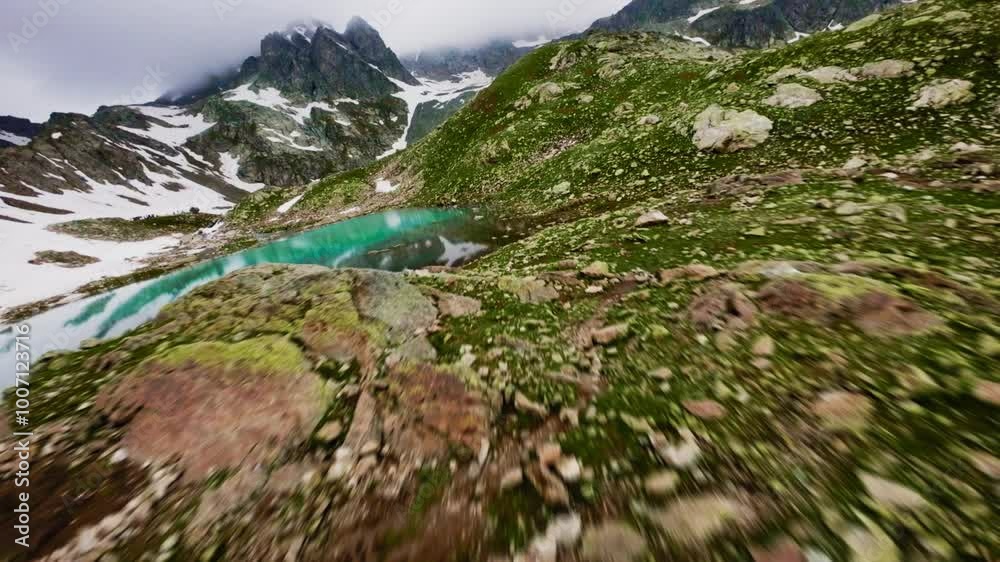 Aerial view from a sports FPV drone low flight over the cascades of a river that flows into a mountain lake. Mountain reservoirs high in the mountains. Flying at high speed very low