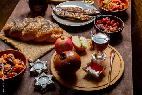 Canvastavla Challah, honey, apple and pomegranate and wine and chelnt and fish on the table