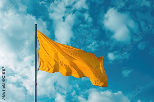 A bright yellow flag waving high in the clear blue sky