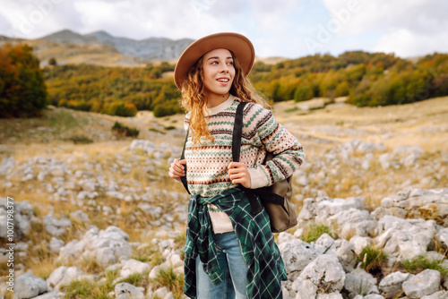 The female tourist carefully navigated the rocky terrain with her backpack full of supplies. Autumn landscape. Travel, nature concept