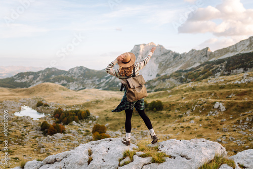 A woman stands on rocky terrain, gazing out at the breathtaking landscape before her. Autumn. Active lifestyle.