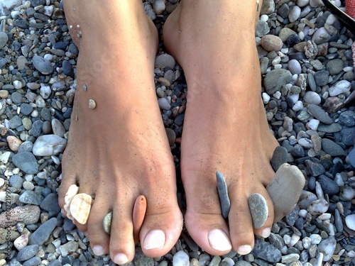 pair of bare feet with pebbles and small rocks tucked between the toes photo