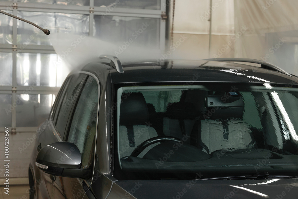 Washing auto with high pressure water jet at car wash, closeup Washing auto with high pressure water jet at car wash, closeup