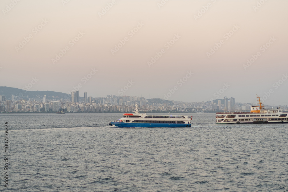 Ferry boats navigate the waters near Istanbul at dusk, with the city skyline glowing in the background, creating a serene atmosphere