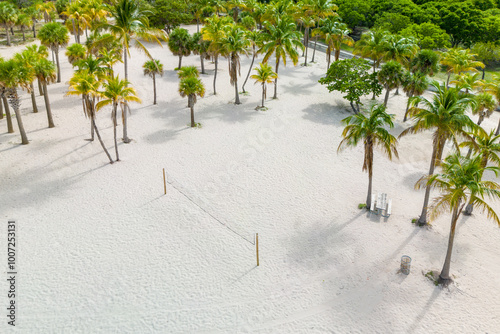 Fototapeta Naklejka Na Ścianę i Meble -  Empty sandy beach with volleyball net, surrounded by palm trees and scenic coastline