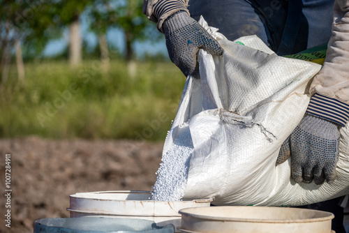 A farmer fills chemicals into the tank of a large agricultural drone to fertilize a planted field.