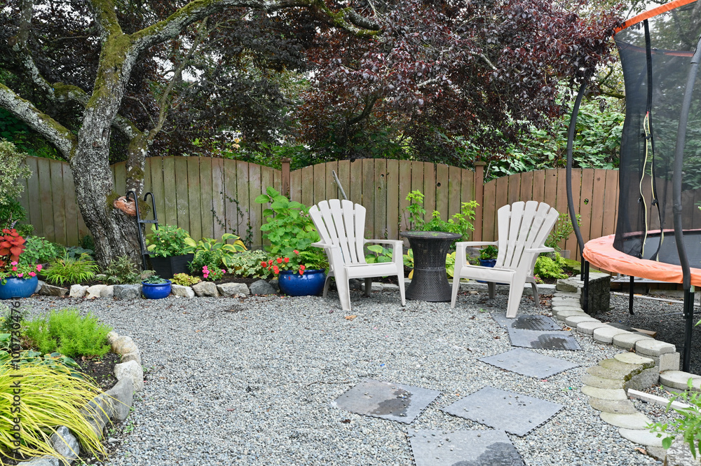 Obraz premium Backyard patio and garden space designed to share space for kids play area and trampoline. Multi use spaces in home landscaped outdoor spaces