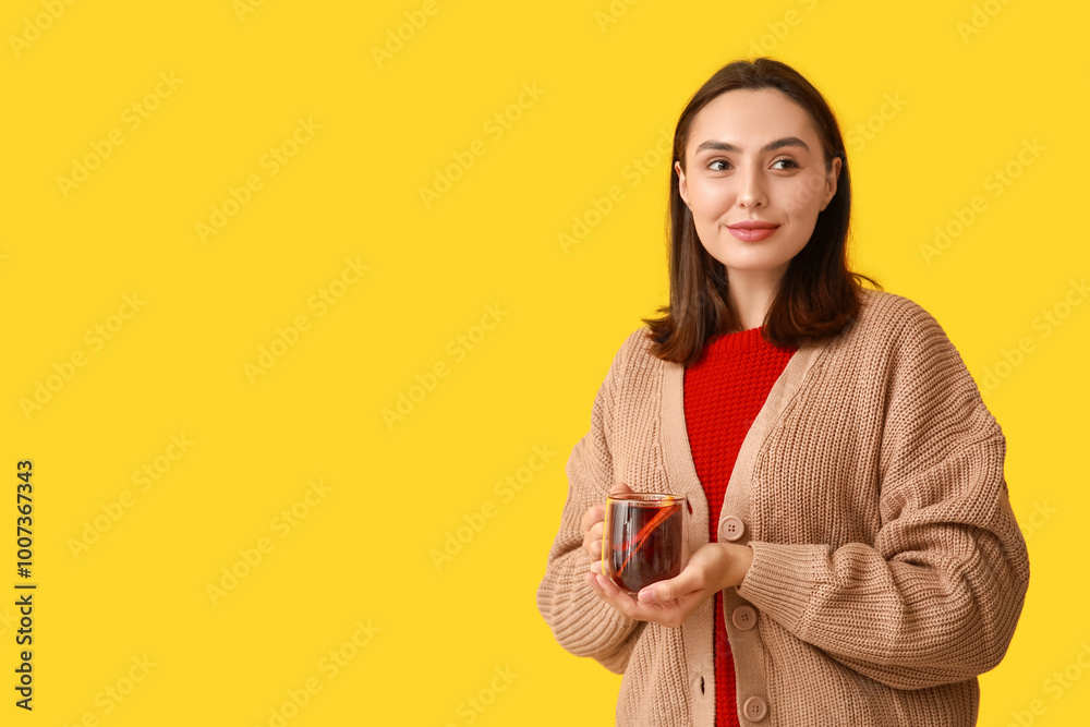 Young woman with glass cup of hot mulled wine on yellow background Young woman with glass cup of hot mulled wine on yellow background