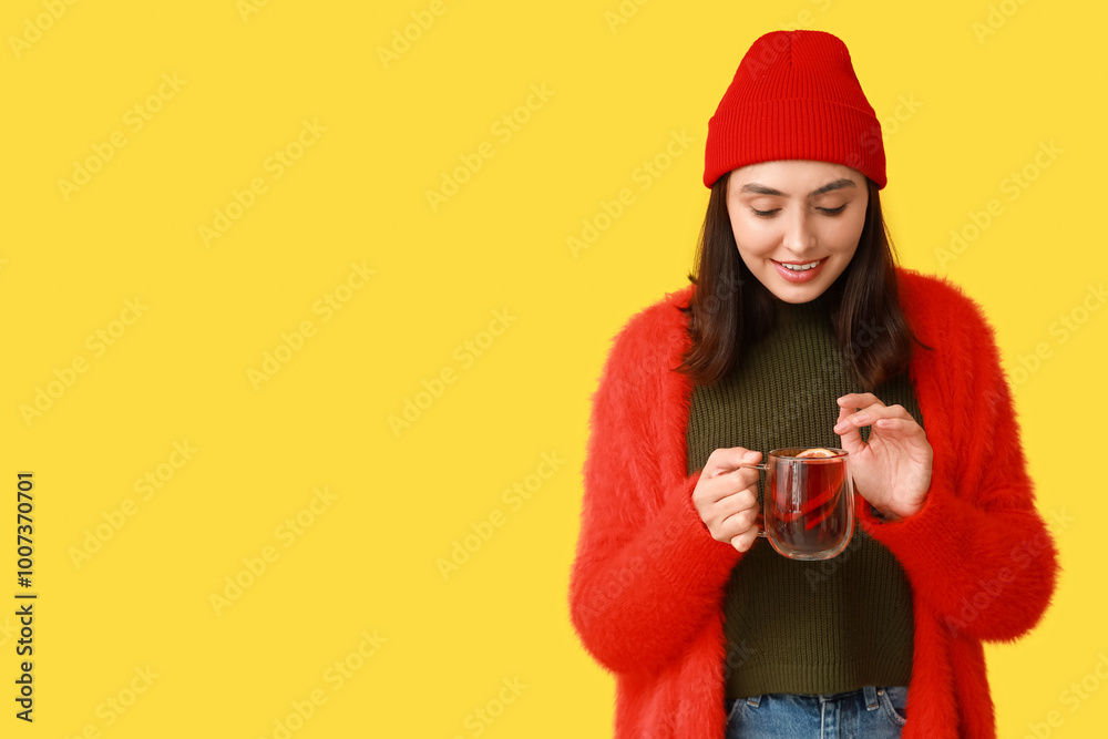 Εκτύπωση καμβά Young woman with glass cup of hot mulled wine on yellow background