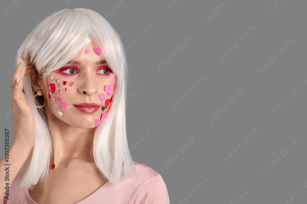 Young woman in white wig with beautiful makeup and paper hearts on grey background. Valentine's Day celebration