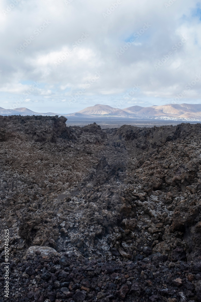 volcanic landscape in the national park of Timafaya, with a sea of lava and volcanic magma rocks, with volcanoes in the background, Lanzarote, Canary Island, vertical volcanic landscape in the national park of Timafaya, with a sea of lava and volcanic magma rocks, with volcanoes in the background, Lanzarote, Canary Island, vertical
