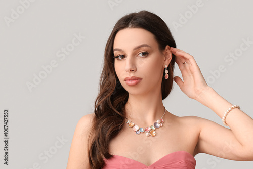 Beautiful woman with jewelry on grey background