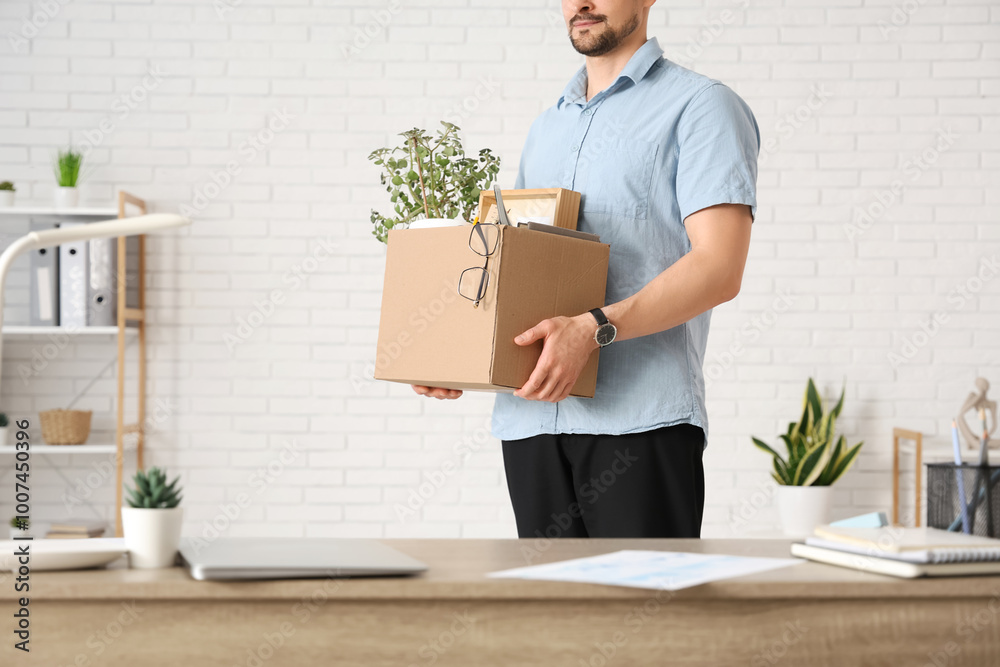 Fired young man holding box of personal stuff in office, closeup Fired young man holding box of personal stuff in office, closeup