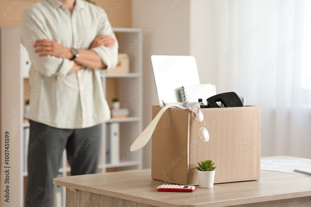 Fototapeta premium Fired young man with box of personal stuff in office, closeup