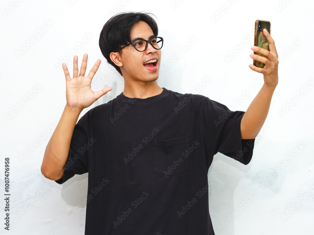 Portrait of a happy young Asian man in a black t-shirt taking a selfie with his mobile phone against an isolated white background, perfect for advertisement. Portrait of a happy young Asian man in a black t-shirt taking a selfie with his mobile phone against an isolated white background, perfect for advertisement.