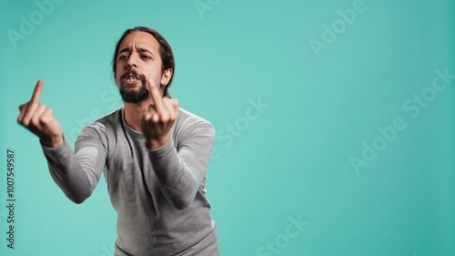Irked man fighting with friend, doing middle finger sign gesturing, isolated over studio background. Outraged person arguing during conversation, doing obscene hand gestures, camera B