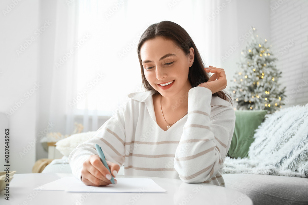 Beautiful young woman writing Christmas letter to Santa in living room Beautiful young woman writing Christmas letter to Santa in living room