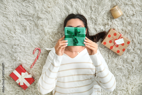 Beautiful young woman with Christmas gift boxes lying on carpet in living room