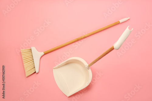 Cleaning broom and dustpan on pink background, flat lay