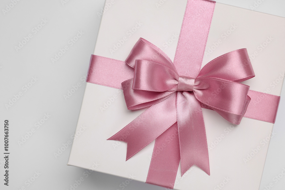 Gift box with pink bow on light grey background, top view Gift box with pink bow on light grey background, top view
