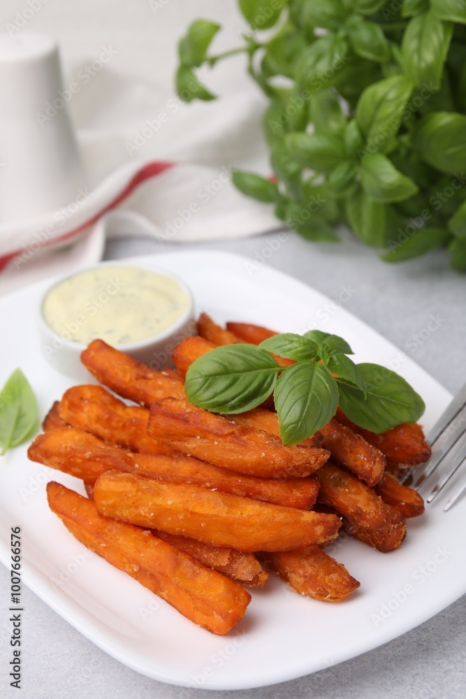 Sweet potato fries, basil and sauce on light grey table, closeup Sweet potato fries, basil and sauce on light grey table, closeup