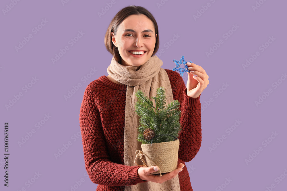 Young woman with Christmas tree in pot and snowflake on purple background Young woman with Christmas tree in pot and snowflake on purple background