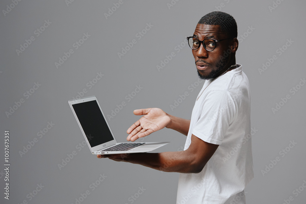 African American male model with laptop, casual outfit, surprised expression, gray background, technology concept, professional setting, showcasing modern lifestyle and innovation African American male model with laptop, casual outfit, surprised expression, gray background, technology concept, professional setting, showcasing modern lifestyle and innovation