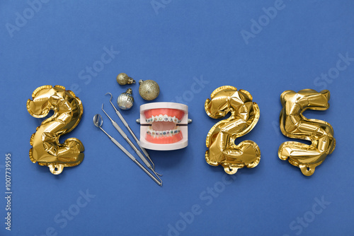 Figure 2025 with dentist's tools, jaw model and Christmas balls on blue background