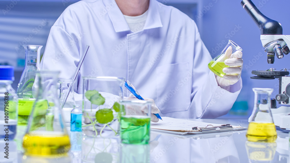 A modern lab setting features a scientist in a white coat examining a green liquid beaker, recording observations in a laboratory filled with experimental tools, solutions, and specimens. A modern lab setting features a scientist in a white coat examining a green liquid beaker, recording observations in a laboratory filled with experimental tools, solutions, and specimens.