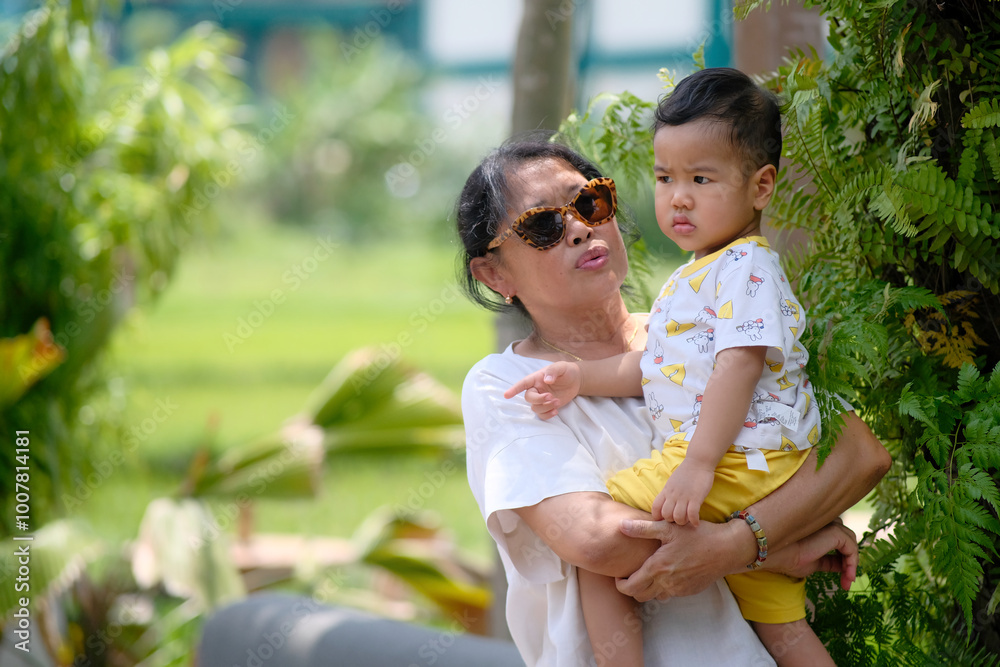 A middle-aged woman holding her son in a botanical garden A middle-aged woman holding her son in a botanical garden