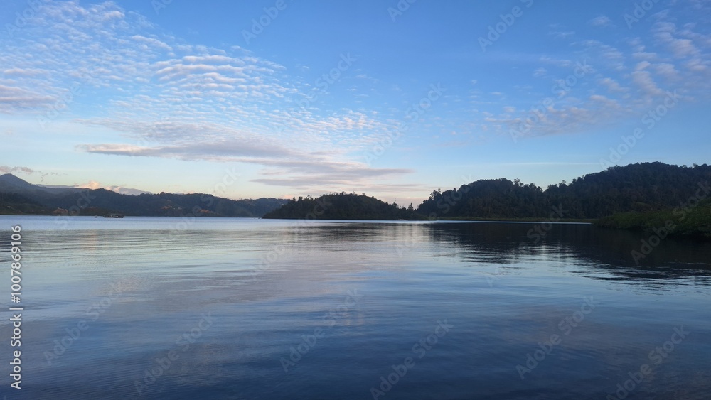 Fototapeta premium Beautiful afternoon views. The hills dark, the sky still blue. Calm sea. The picture was taken from the middle of the sea. Mandeh, West Sumatra, Indonesia