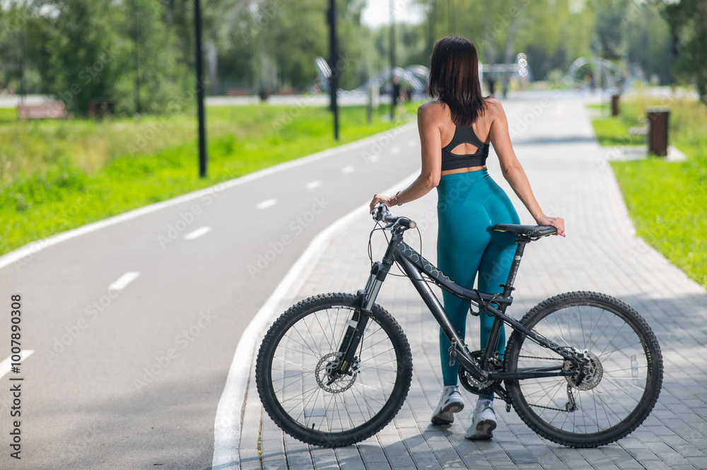 Rear view of Caucasian woman riding bike in park. Rear view of Caucasian woman riding bike in park.