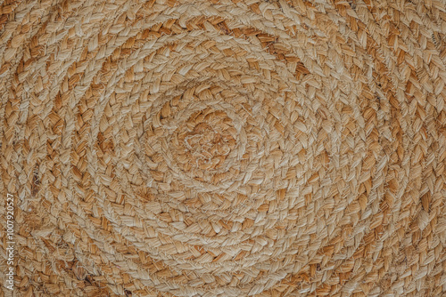 Textured natural woven round mat with spiral patterns on a neutral background