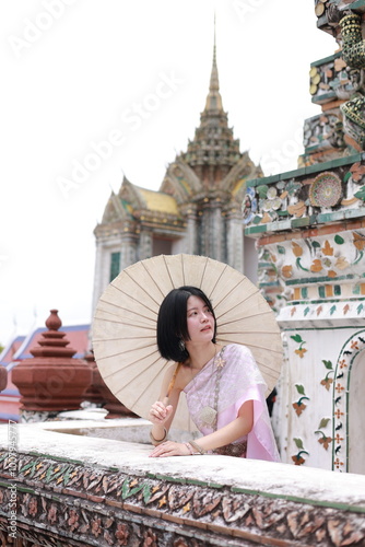Young Asian woman in traditional thai costumes at Wat Arun Ratchawararam (the Temple of Dawn) in Bangkok, Thailand.