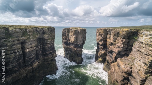 Majestic Coastal Rock Formation with Crashing Waves Amid Moody Cloudy Sky