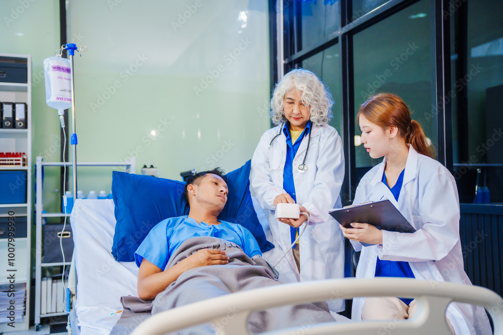 Fototapeta premium A middle-aged man lies bedridden on hospital bed, closely monitored by an old Asian woman doctor and young nurse. They assess his symptoms, including heart and lung conditions, offer advice.