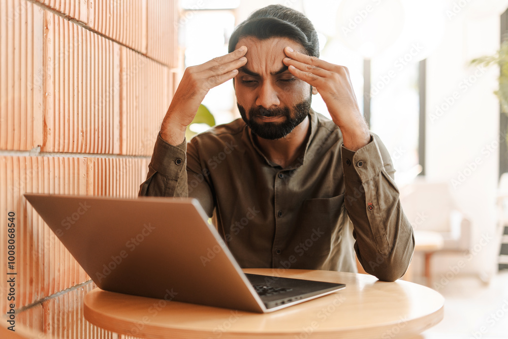 Stressed Indian businessman using laptop working, headache, something wrong, failed business Stressed Indian businessman using laptop working, headache, something wrong, failed business