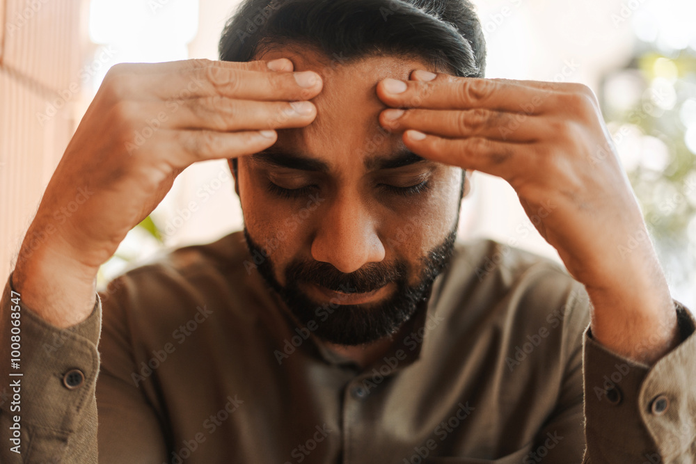 Tired, unhappy Indian businessman suffering from headache touching his temples, closeup Tired, unhappy Indian businessman suffering from headache touching his temples, closeup