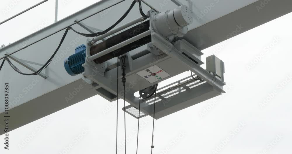 Electric hoisting machine moving overhead from the left to the right side of the frame. Electric hoisting machine moving overhead from the left to the right side of the frame.